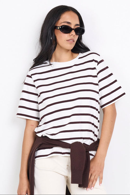 Woman wearing a black and white striped shirt with white pants on a white background