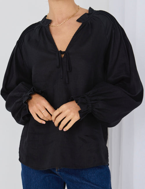 model wears a black linen top