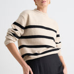 model wears a beige stripe knit and a black linen skirt