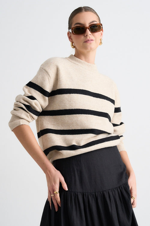 model wears a beige stripe knit and a black linen skirt