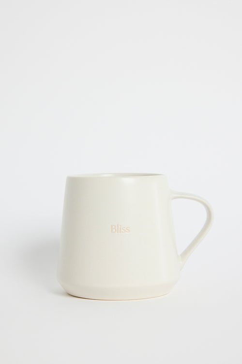 Cream-coloured ceramic mug with the word ‘Bliss’ embossed on the front, photographed on a white background
