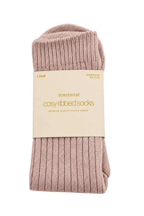 Blush pink cosy ribbed socks in Stories Be Told packaging, made with soft plush fibres.