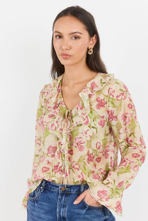 Woman wearing a floral blouse and blue jeans on a white background