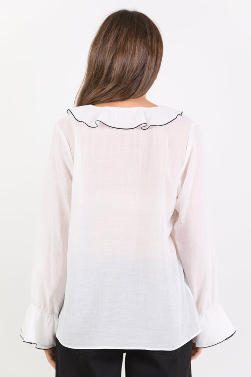 Woman wearing a white blouse with black trim on a white background