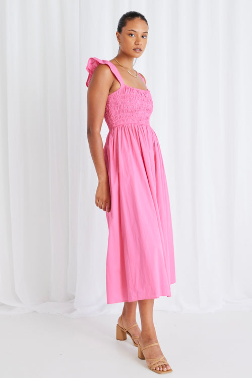 model wears long pink midi dress and tan heels. 