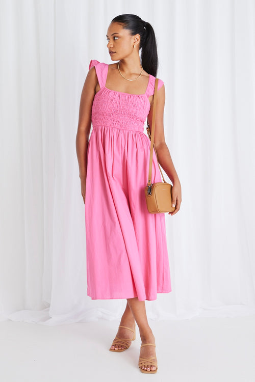 model wears long pink midi dress and tan heels. 