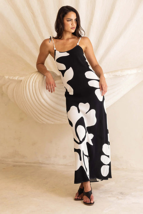 Woman wearing a black and white floral dress in front of a large shell sculpture.