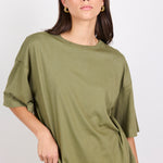Woman wearing an olive green oversized t-shirt against a plain background