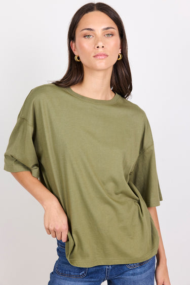 Woman wearing an olive green oversized t-shirt against a plain background
