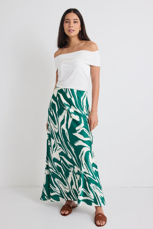 model wears off the shoulder white top and a green zebra print satin skirt