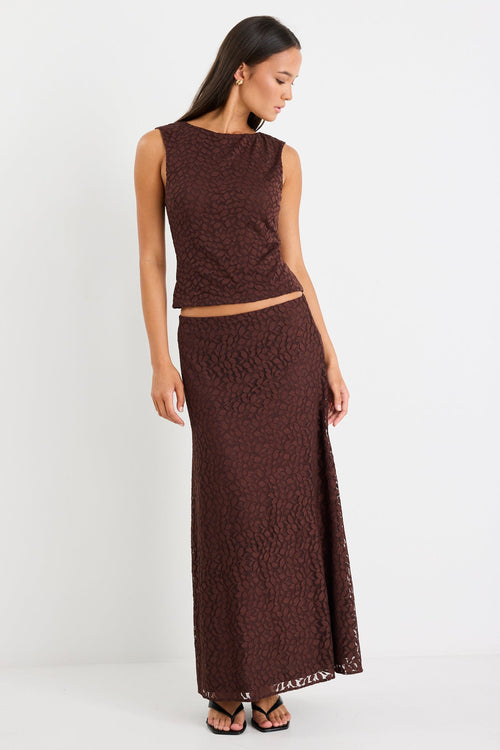 Woman wearing a brown sleeveless top and long skirt on a white background