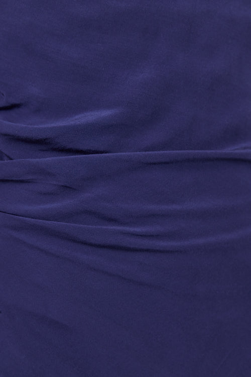 A close-up of draped dark purple fabric with soft folds and a smooth texture.