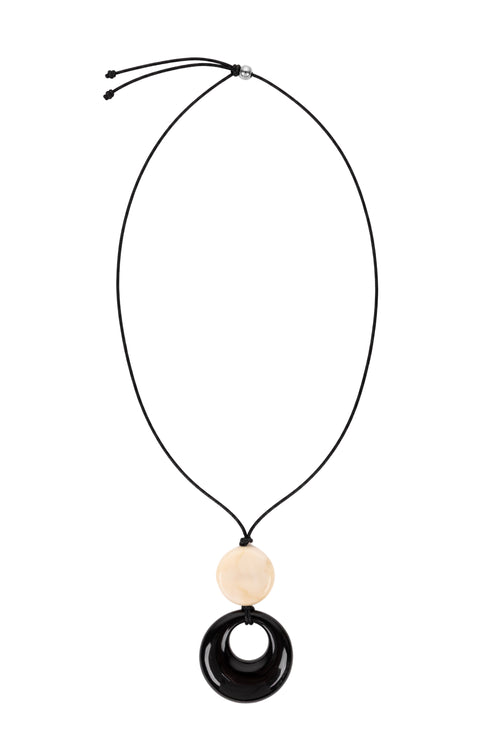 A black cord necklace featuring a round beige wooden bead and a larger brown circular pendant with a cutout, shown against a plain white background.