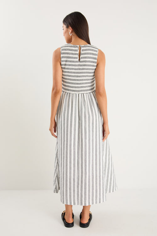 Woman wearing a black white striped dress and strappy black sandals 