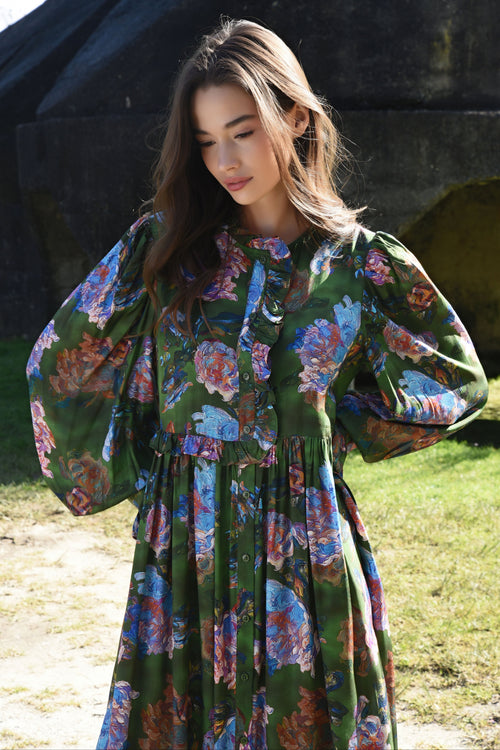 Woman wearing a floral dress standing outdoors with a dark background