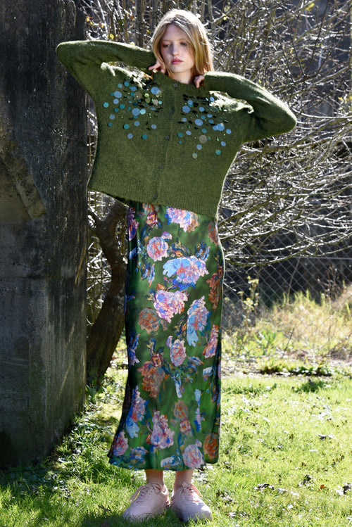 Person wearing a green floral dress and green cardigan outdoors.