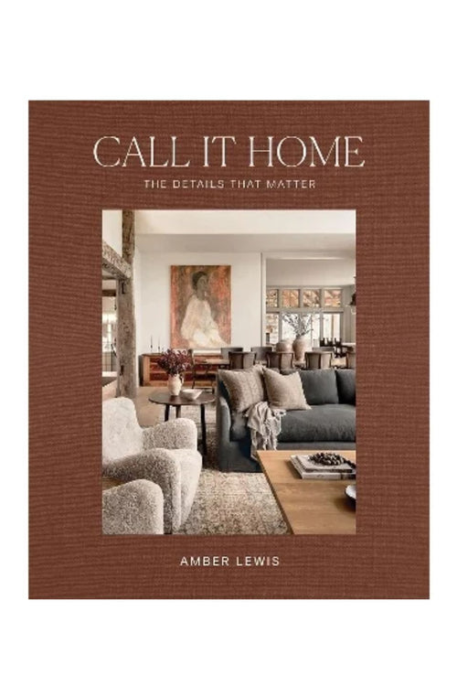 The front cover of the book 'Call It Home: The Details That Matter' by Amber Lewis. The cover features a textured brown border with the title in white serif font and a central photograph of a cozy, modern living room.