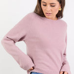 Woman wearing a pink sweater and blue jeans on a white background