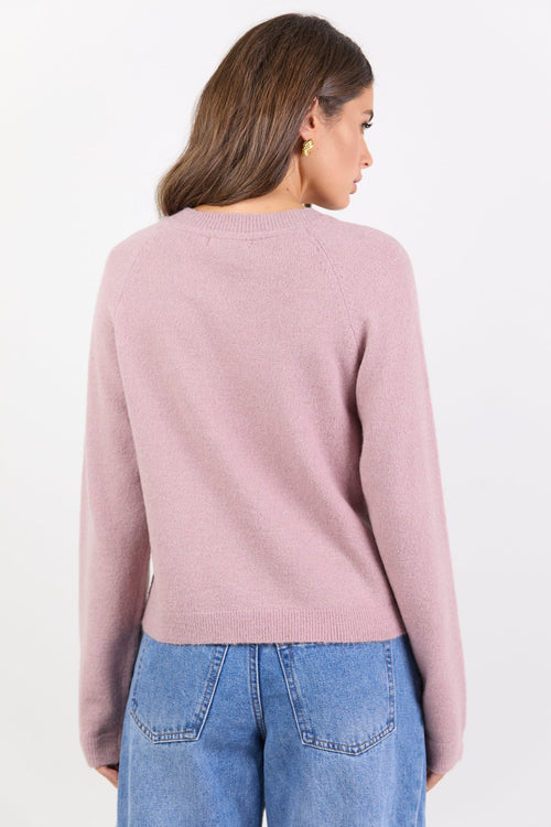 Woman wearing a pink sweater and blue jeans on a white background