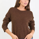 Woman wearing a brown sweater and blue jeans on a white background