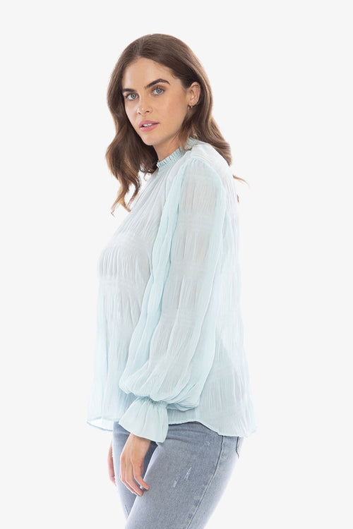 model in pale blue long sleeve top and blue jeans
