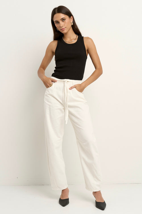 model wears a ecru barrel leg jeans with black tank top