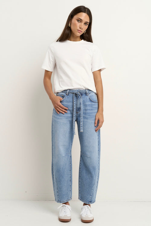 model wears a light blue barrel leg jean with a white t-shirt