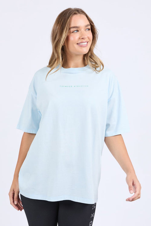Woman wears an oversized pale blue t-shirt with short sleeves, a round neckline, and small 