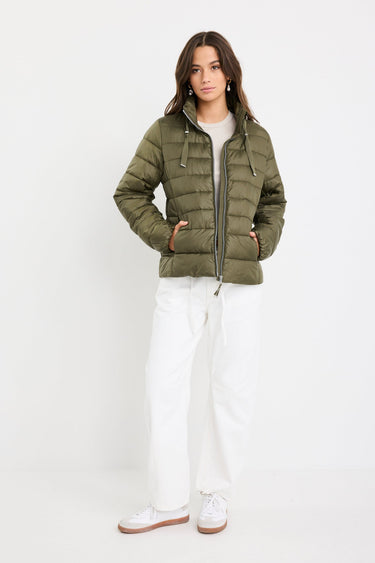 Woman wearing a green puffer jacket with a plain white background