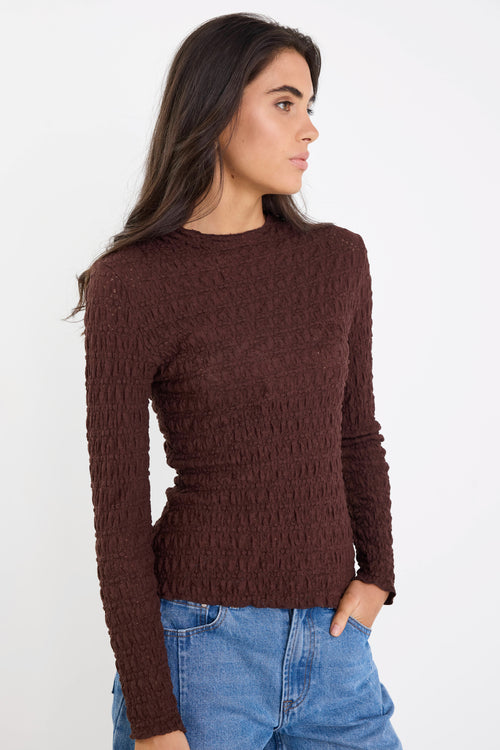 Woman wearing a brown knitted sweater and blue jeans on a white background