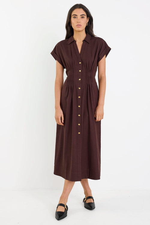 Woman wearing a brown dress with buttons on a white background