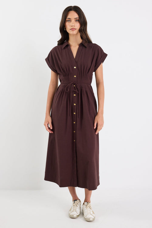 Woman wearing a brown dress with buttons on a white background