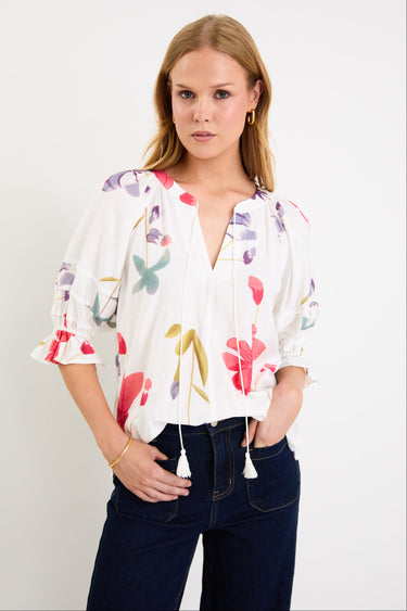 Woman wearing a cream floral poppy top and blue jeans