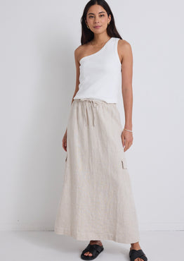 model wears natural linen maxi skirt and white one shoulder top