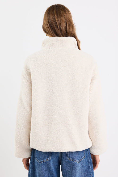 Person wearing a white jacket and blue jeans on a white background