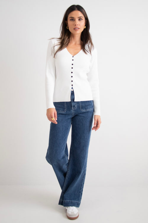 model wears a white cardigan with dark blue jeans