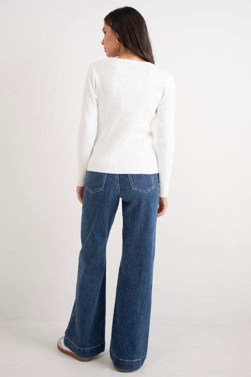 model wears a white cardigan with dark blue jeans