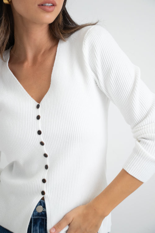 model wears a white cardigan with dark blue jeans