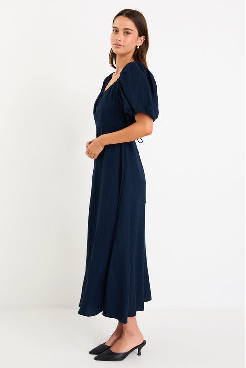 Woman wearing navy blue maxi dress with puff sleeves.