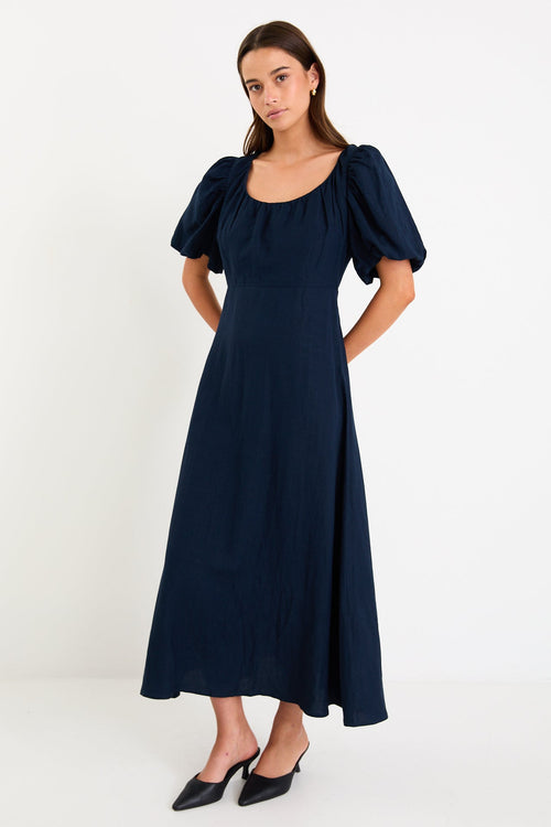 Woman wearing navy blue maxi dress with puff sleeves.