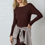 Woman wearing a brown ribbed maxi dress with long sleeves and a brown striped shirt tied around the waist.