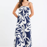 Woman wearing a navy and white printed maxi dress with tie straps, shirred back, and a flowing full-length silhouette.