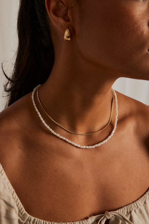 model wearing pearl necklace and gold necklace