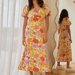 model in long orange red yellow and purple floral dress and white sneakers