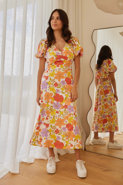 model in long orange red yellow and purple floral dress and white sneakers
