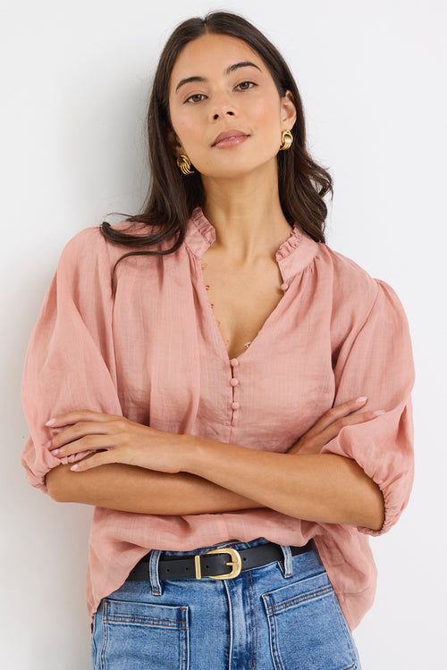 model wears a pink blouse with light blue jeans