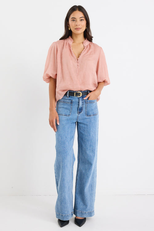 model wears a pink blouse with light blue jeans