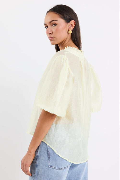 woman wearing yellow sheer blouse with blue jeans