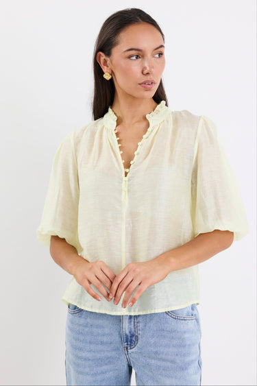 woman wearing yellow sheer blouse with blue jeans