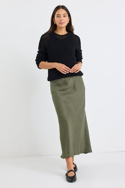 Woman wearing a black top and green skirt on a white background